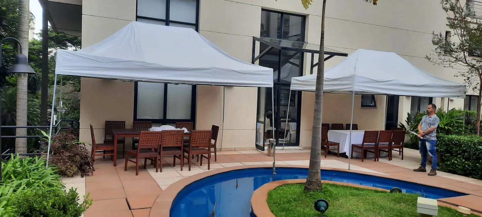 Tendas montadas em área externa residencial com mesas e piscina